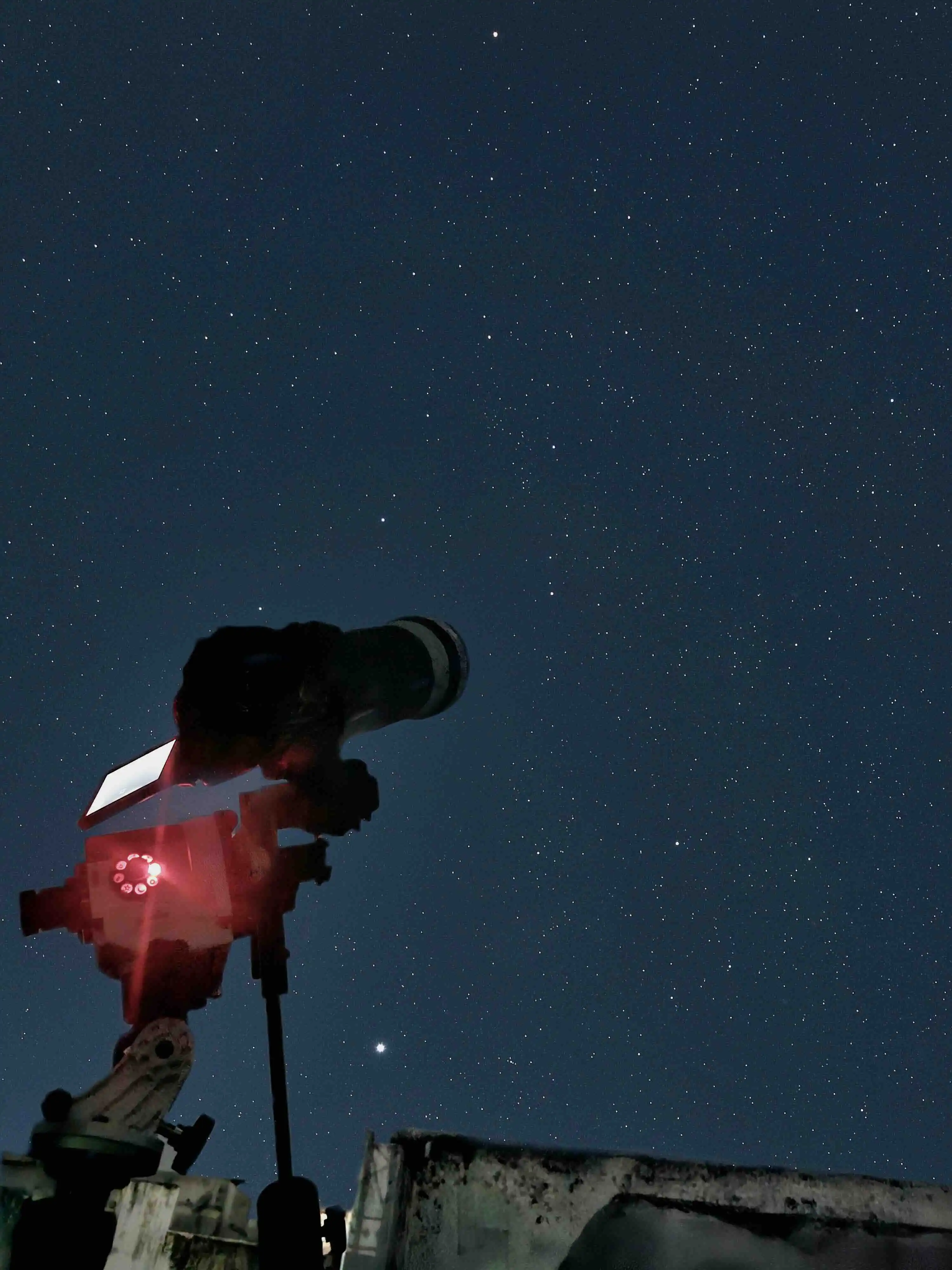 A camera on a tripod beneath a sky full of stars
